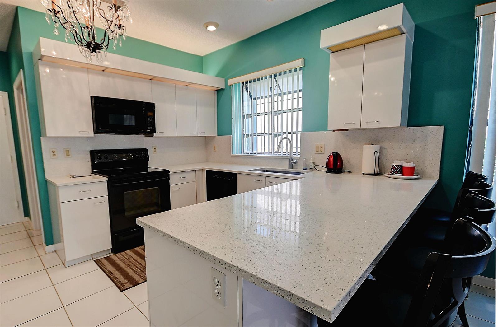 A kitchen features white cabinets, a speckled countertop, black appliances, and teal walls — 19356 Cherry Hills Terrace, Boca Raton FL 33498, BOCA RATON, FL
