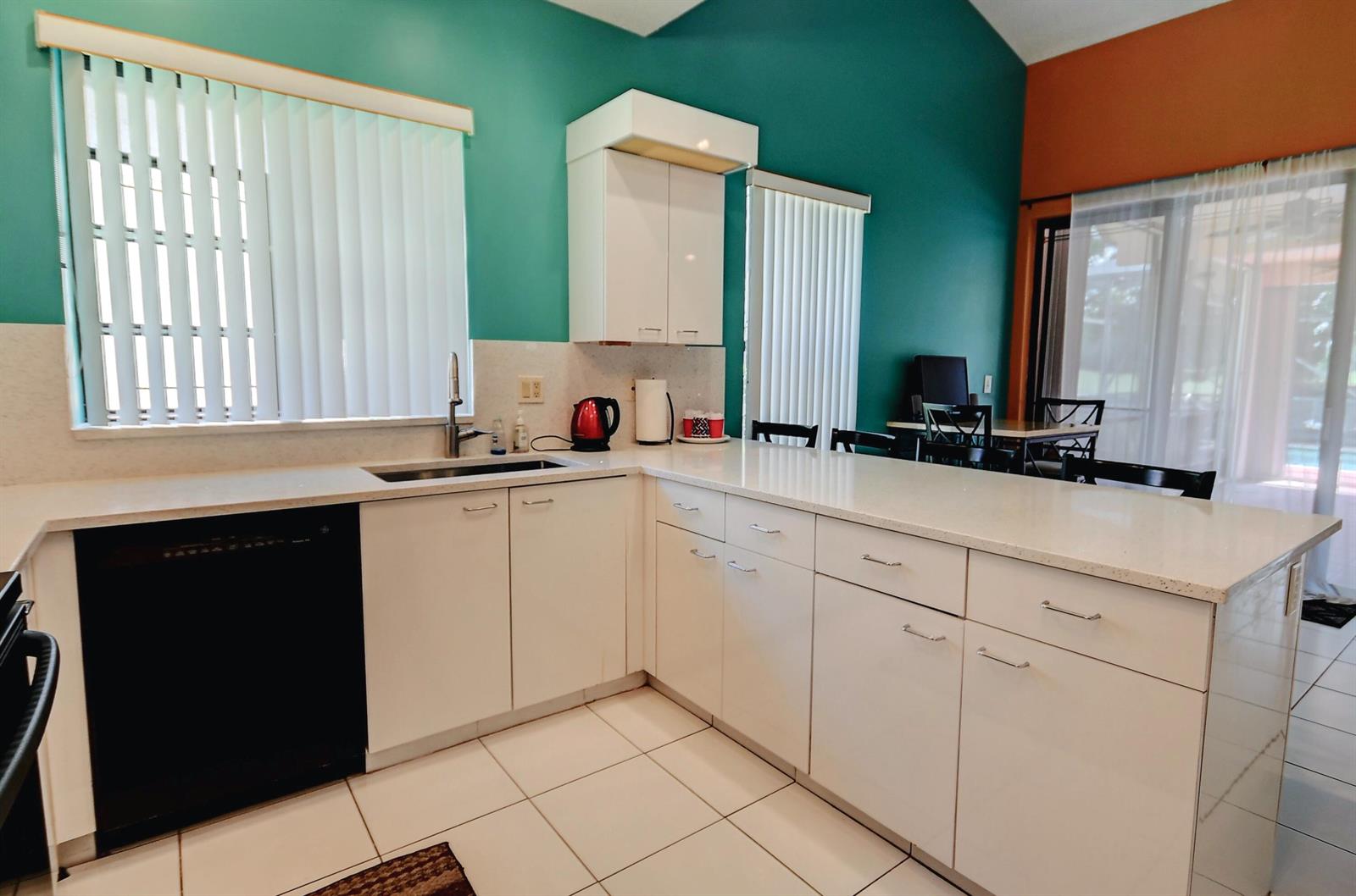 A kitchen with white cabinets, light countertops, teal walls, and a black dishwasher — 19356 Cherry Hills Terrace, Boca Raton FL 33498, BOCA RATON, FL