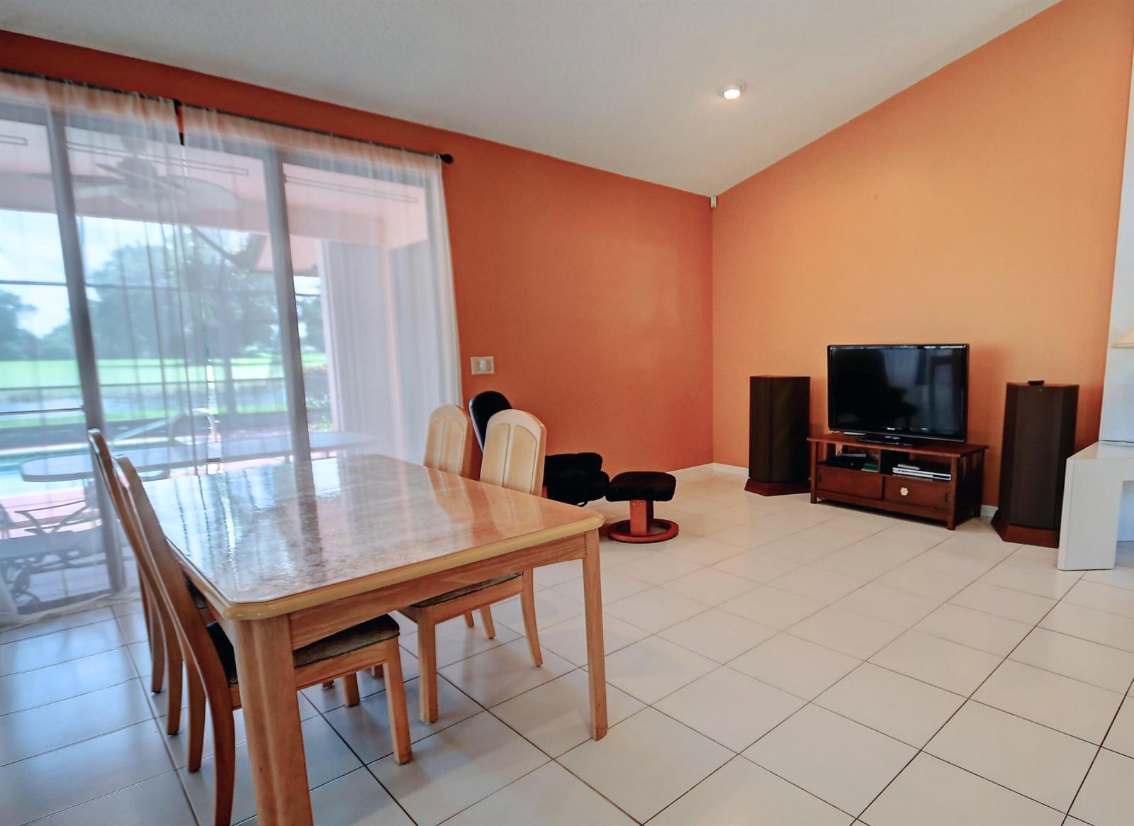 A dining area and living space with orange walls, tile floors, and a sliding door — 19356 Cherry Hills Terrace, Boca Raton FL 33498, BOCA RATON, FL