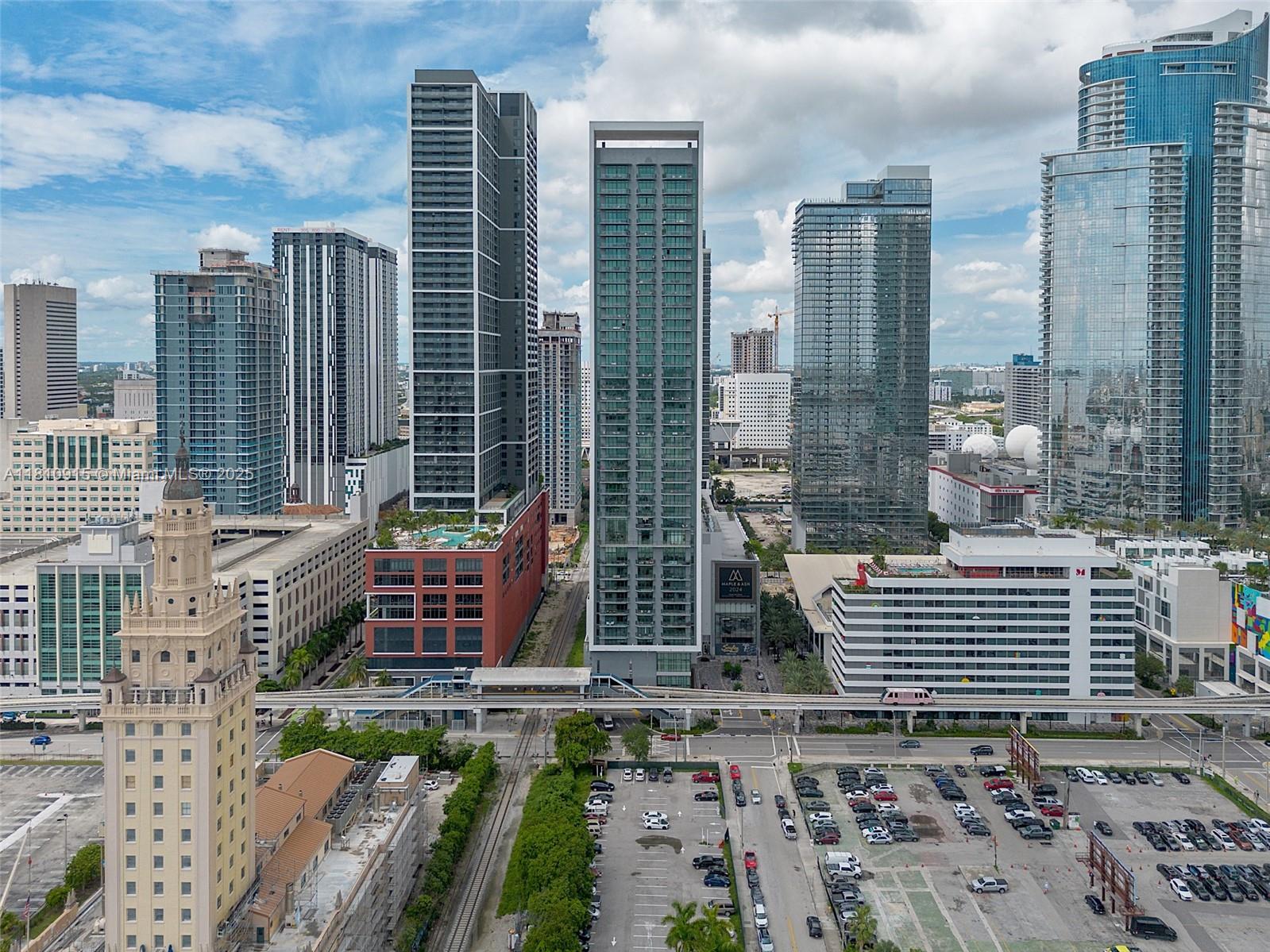 An aerial view of a dense urban skyline featuring modern skyscrapers, a historic tower, and parking lots — 601 NE 1st Ave # 5007, Miami FL 33132, MIAMI, FL
