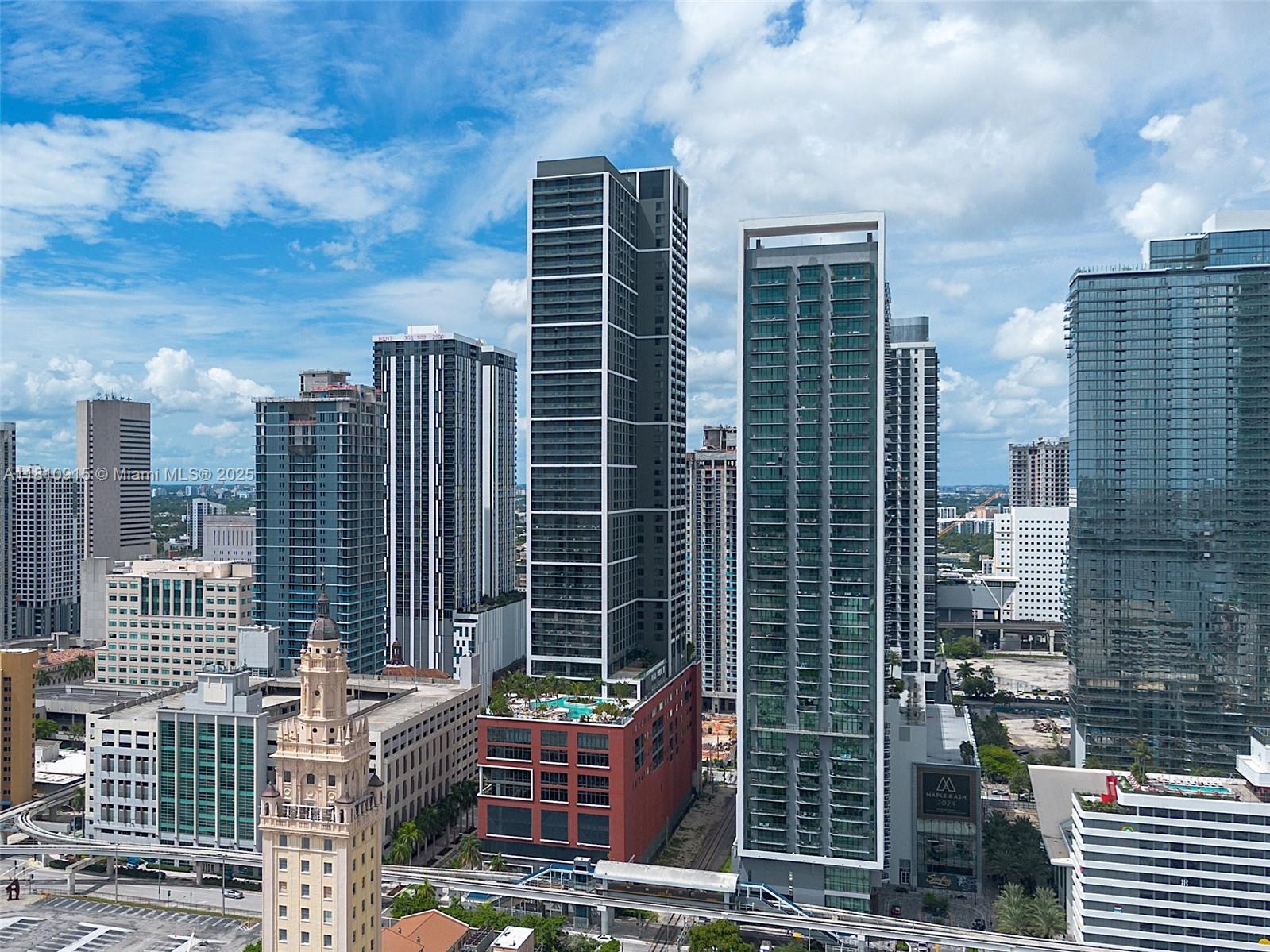 An aerial view shows several modern high-rise buildings and a historic tower in a city — 601 NE 1st Ave # 5007, Miami FL 33132, MIAMI, FL