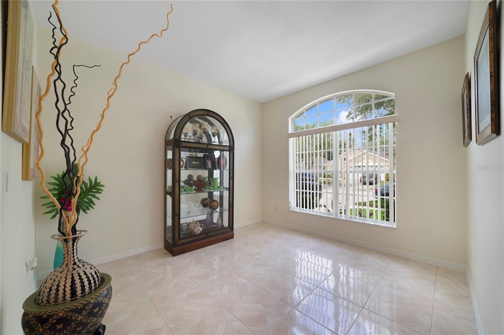 A bright room with light tile flooring, an arched window, and a glass display cabinet — 8376 PORT LANCASHIRE DRIVE, ORLANDO, FL