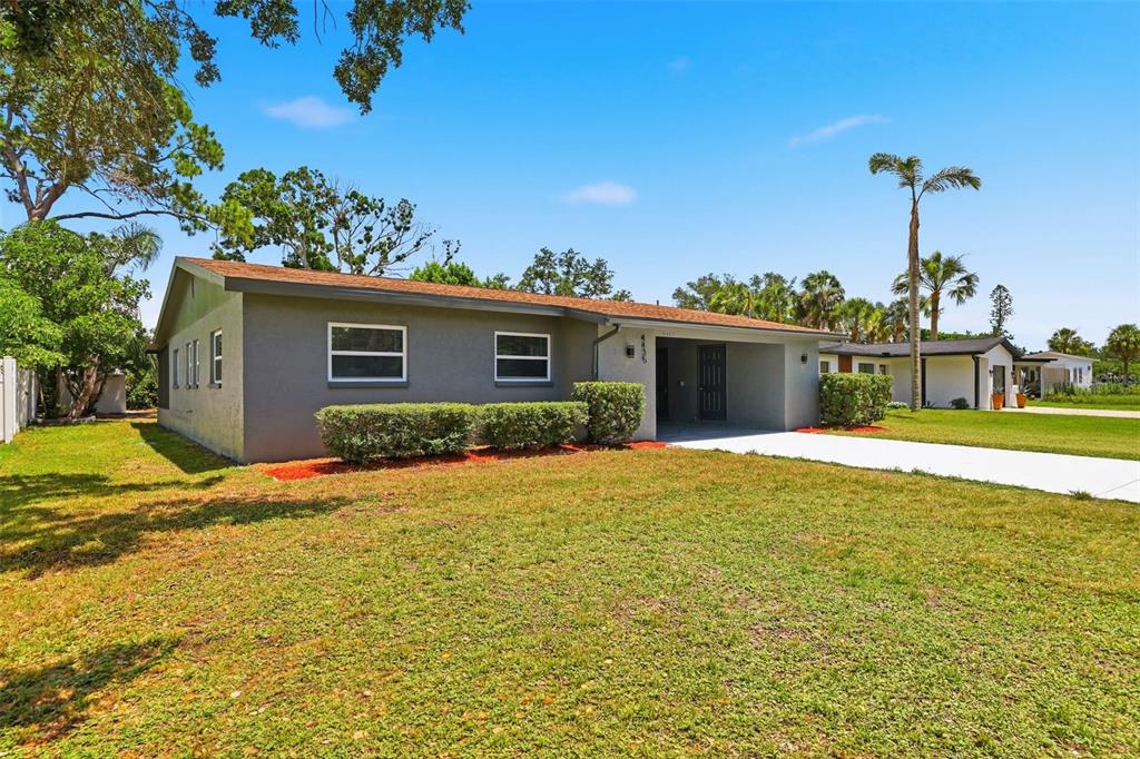 A single-story gray house with a flat roof, a concrete driveway, and a front lawn — 4435 HUNTINGTON STREET NE, ST PETERSBURG, FL