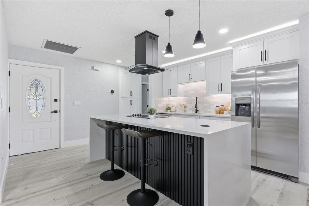 A modern kitchen features a white island with black slat detailing, stainless appliances, and cabinetry — 4435 HUNTINGTON STREET NE, ST PETERSBURG, FL
