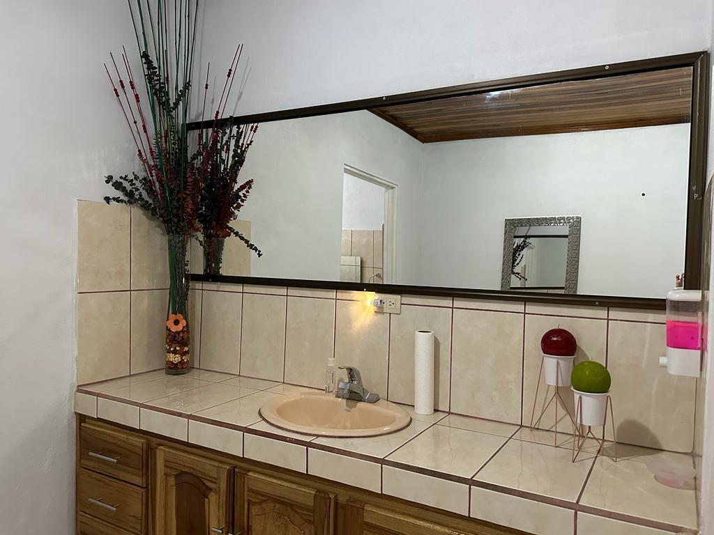 A bathroom vanity with a tiled countertop, beige sink, large mirror, and wooden cabinets — 0000 Hope Garden, 00000, FL