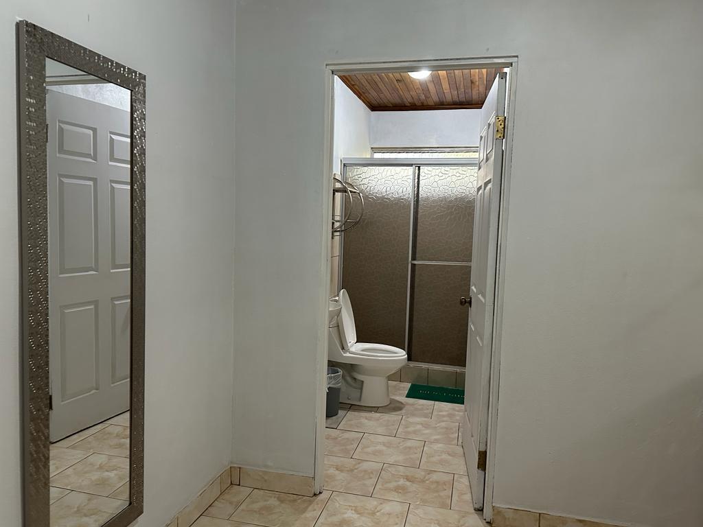 A view from a hallway looking into a bathroom with a toilet and shower stall — 0000 Hope Garden, 00000, FL