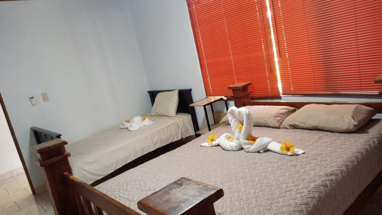 A bedroom features a queen bed and a twin bed with towel swans and orange blinds — 0000 Hope Garden, 00000, FL