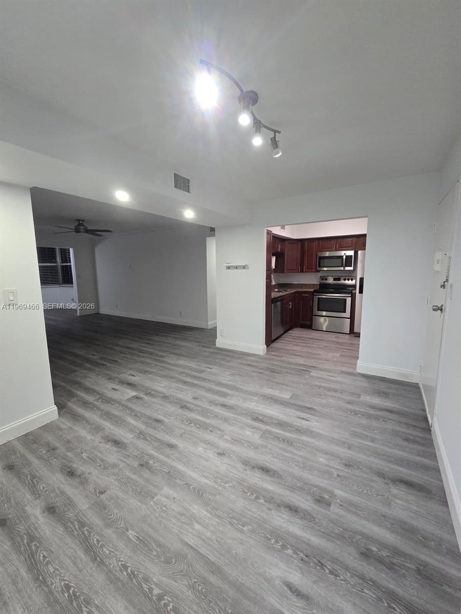 A view of a kitchen with dark cabinets and stainless steel appliances from a living area — 6500 Cypress Rd # 301, Plantation FL 33317, PLANTATION, FL