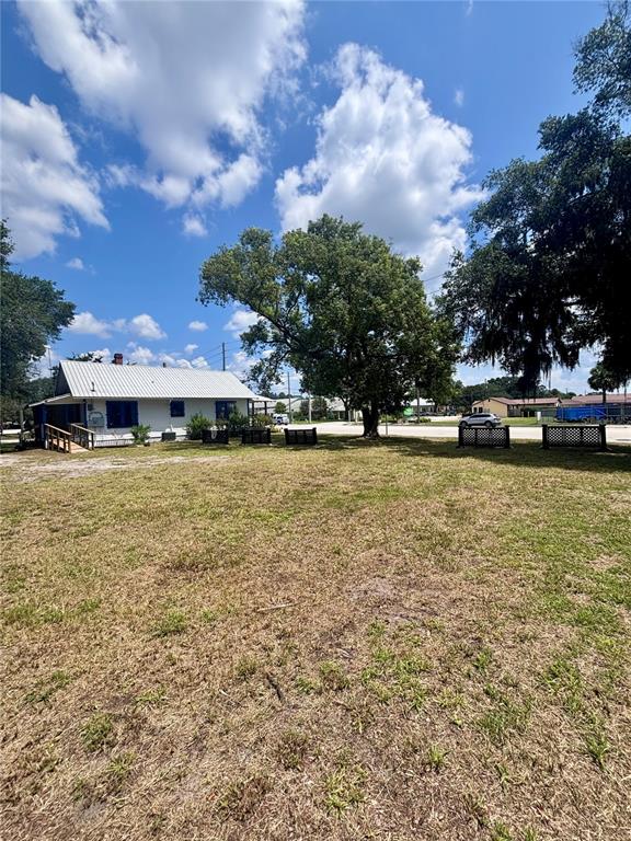 A white house with a metal roof sits on a large, grassy lot with trees — 490 N SPRING GARDEN AVENUE, DELAND, FL