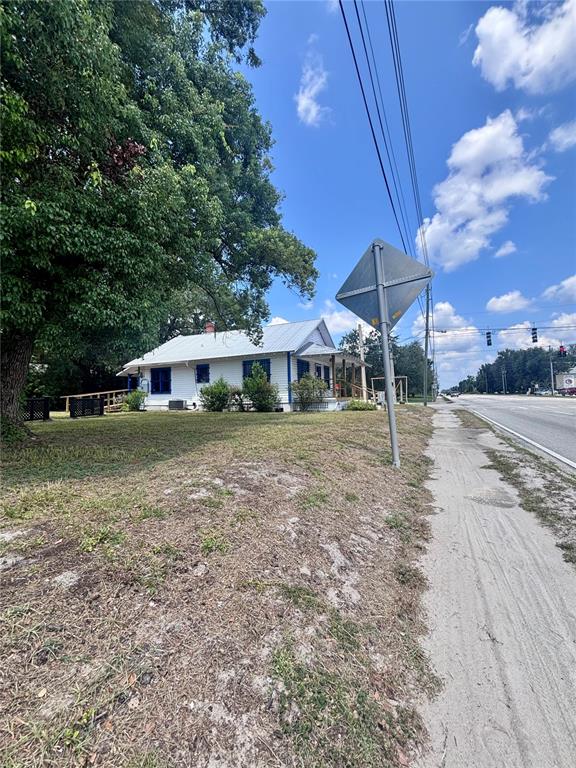 A white, single-story house with a metal roof sits beside a road and sidewalk — 490 N SPRING GARDEN AVENUE, DELAND, FL