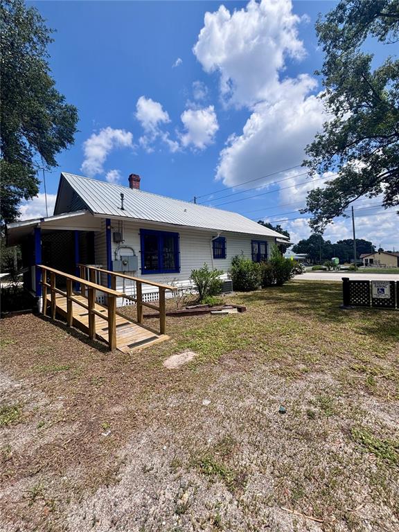 A white, single-story house with a metal roof and a wooden wheelchair ramp — 490 N SPRING GARDEN AVENUE, DELAND, FL