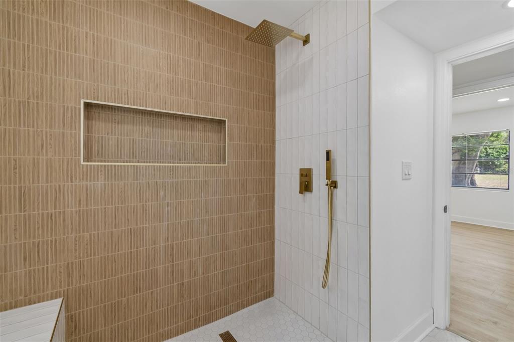 A shower features vertical tan tiles, white wall tiles, gold fixtures, and a recessed niche — 1702 W JOHNSTON AVENUE, TAMPA, FL