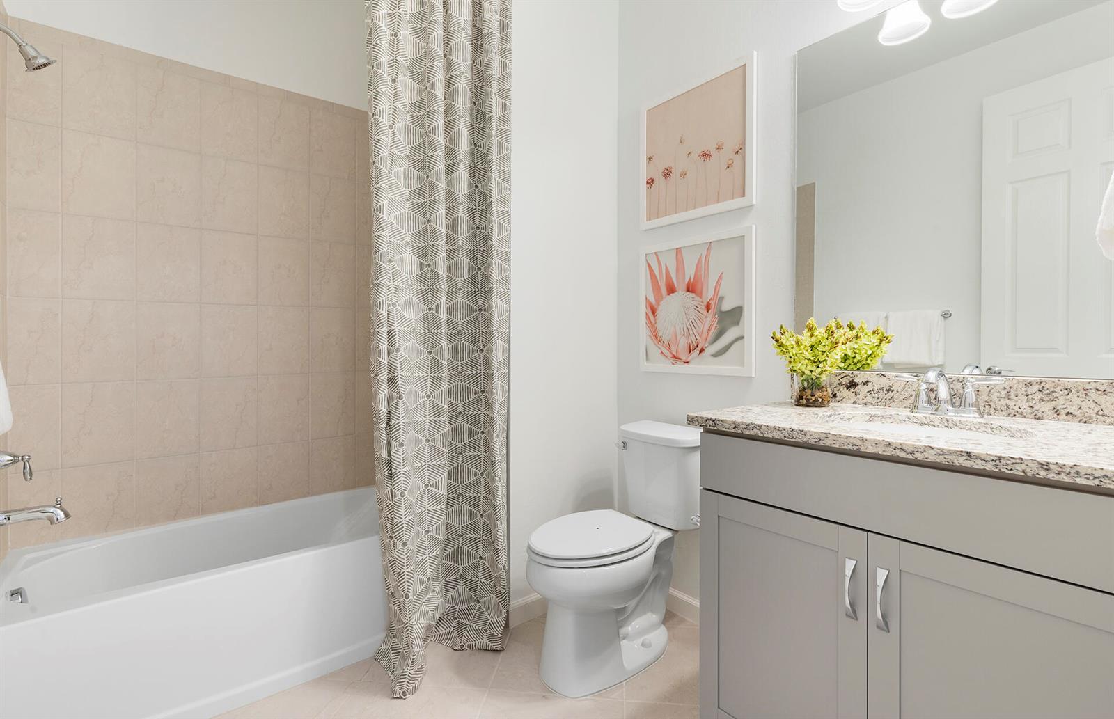 A bathroom featuring a bathtub with a patterned curtain, a toilet, and a gray vanity — 6407 Memorial Lane, Ave Maria FL 34142, AVE MARIA, FL