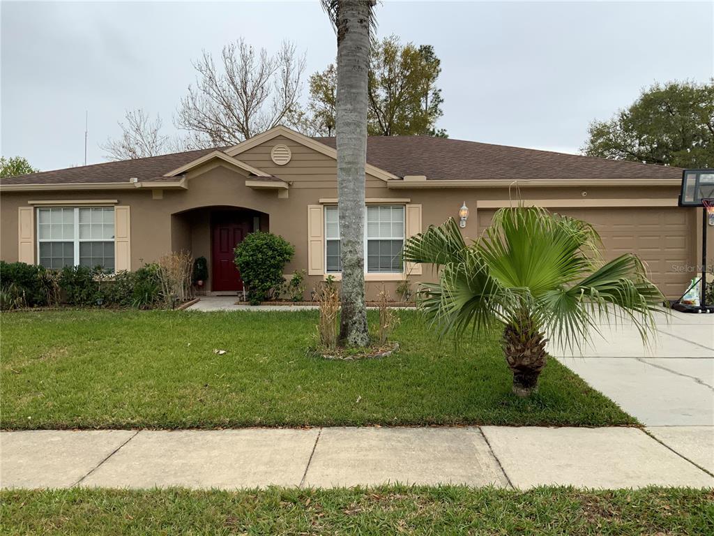 A single-story house with a tan exterior, a red front door, and a palm tree — 1112 JUNIPER HAMMOCK COURT, WINTER GARDEN, FL
