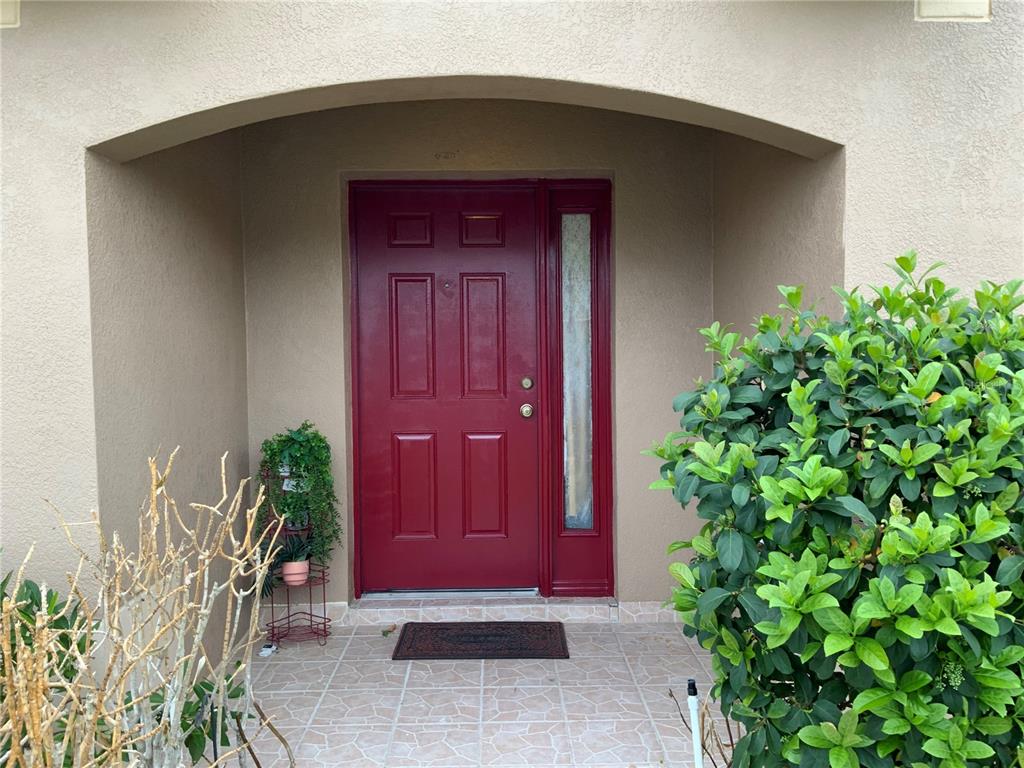 A red front door with a side window is set within a recessed entryway — 1112 JUNIPER HAMMOCK COURT, WINTER GARDEN, FL