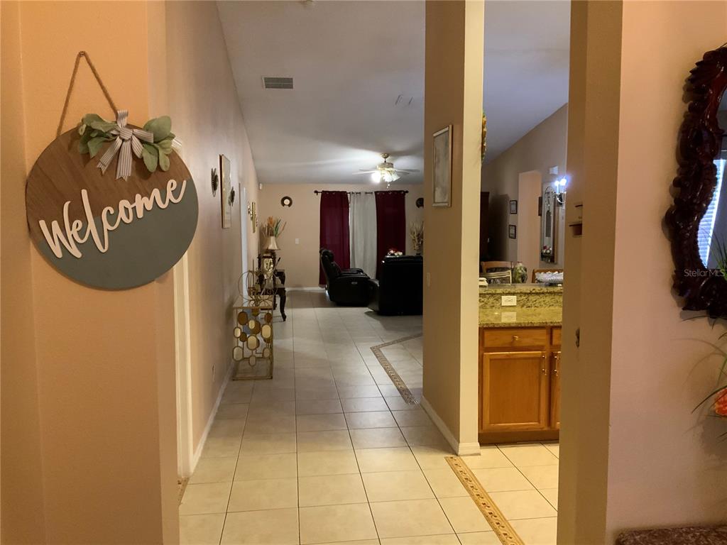 A view from a tiled entryway looking toward a living room and kitchen area — 1112 JUNIPER HAMMOCK COURT, WINTER GARDEN, FL
