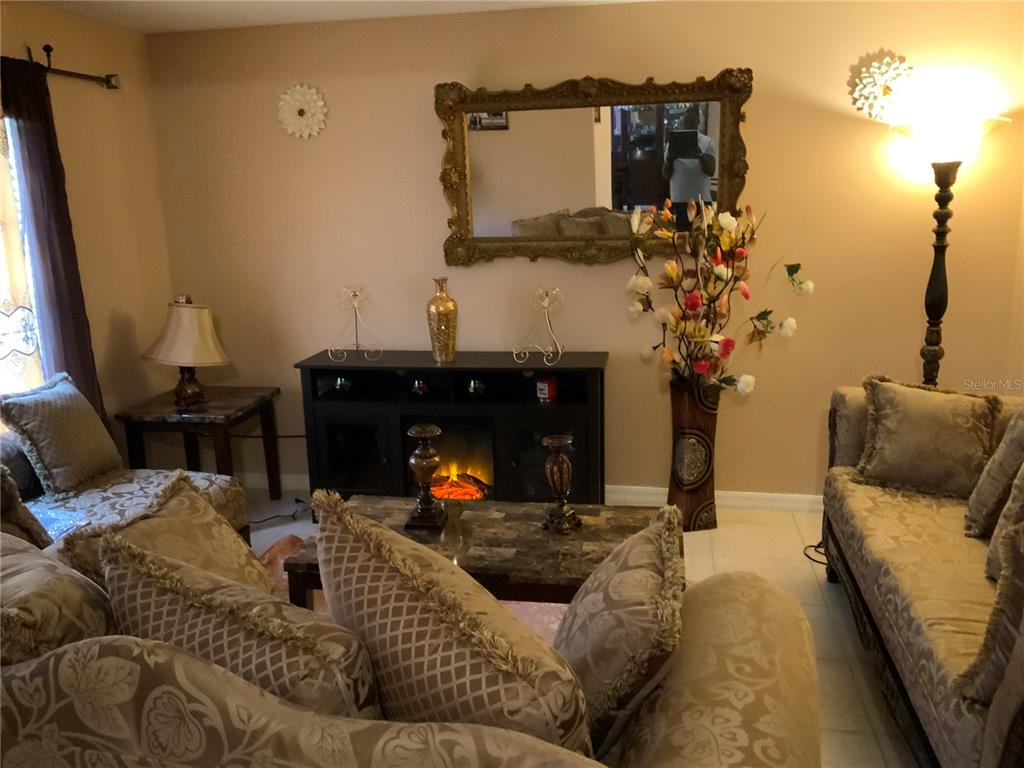 A living room features a fireplace console, a large ornate mirror, and patterned furniture — 1112 JUNIPER HAMMOCK COURT, WINTER GARDEN, FL