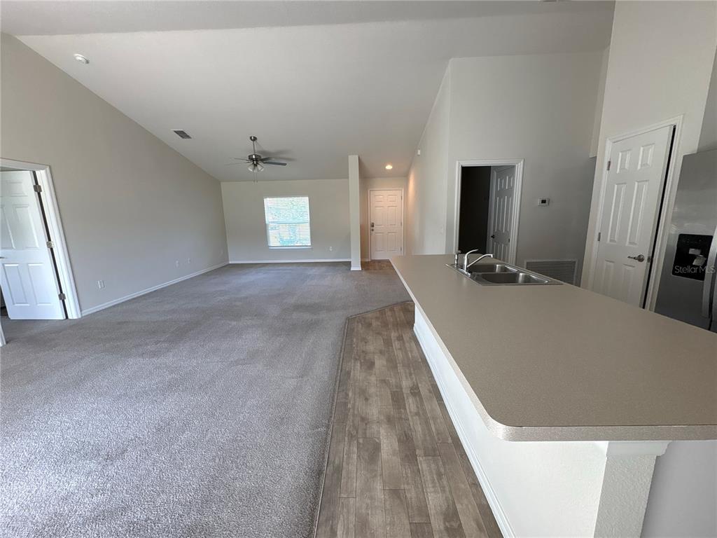 A carpeted living room opens to a kitchen with a breakfast bar and sink — 15415 SW 34TH AVENUE, OCALA, FL