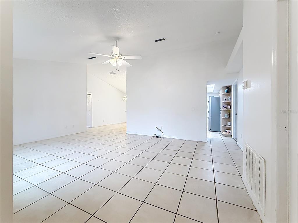 A bright, empty living room features white walls, a ceiling fan, and light-colored floor tiles — 4592 SW GARDENIA COURT, DUNNELLON, FL