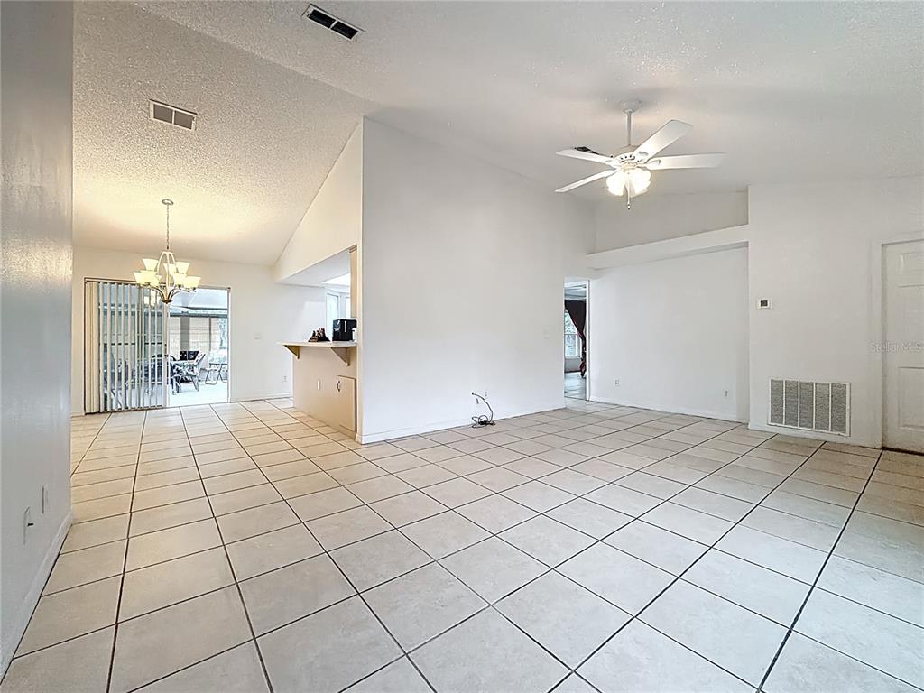 An open-concept living and dining area features white walls, vaulted ceilings, and light-colored tile flooring — 4592 SW GARDENIA COURT, DUNNELLON, FL