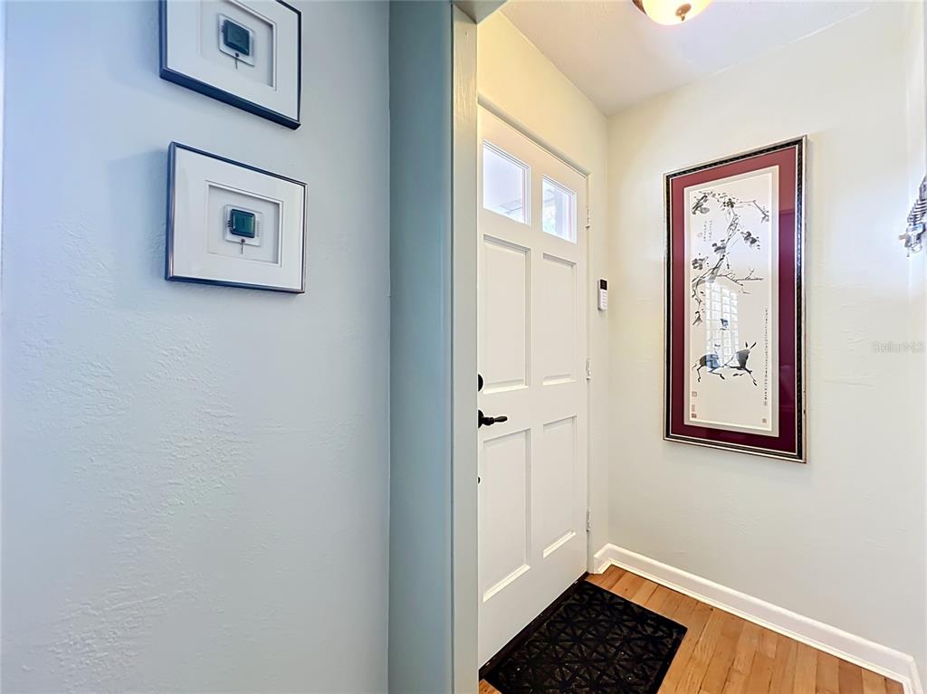 A bright entryway features a white front door, hardwood floors, and framed wall art — 2806 VINE STREET, ORLANDO, FL