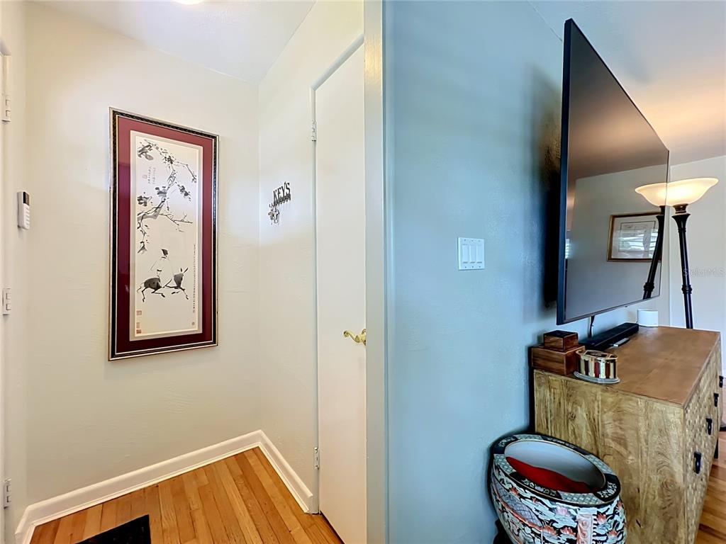 A hallway with hardwood floors, a framed wall art piece, and a closed door — 2806 VINE STREET, ORLANDO, FL