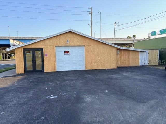 A single-story building with plywood siding, a white garage door, and a glass-paneled entry door — 1601 5TH AVENUE N, ST PETERSBURG, FL