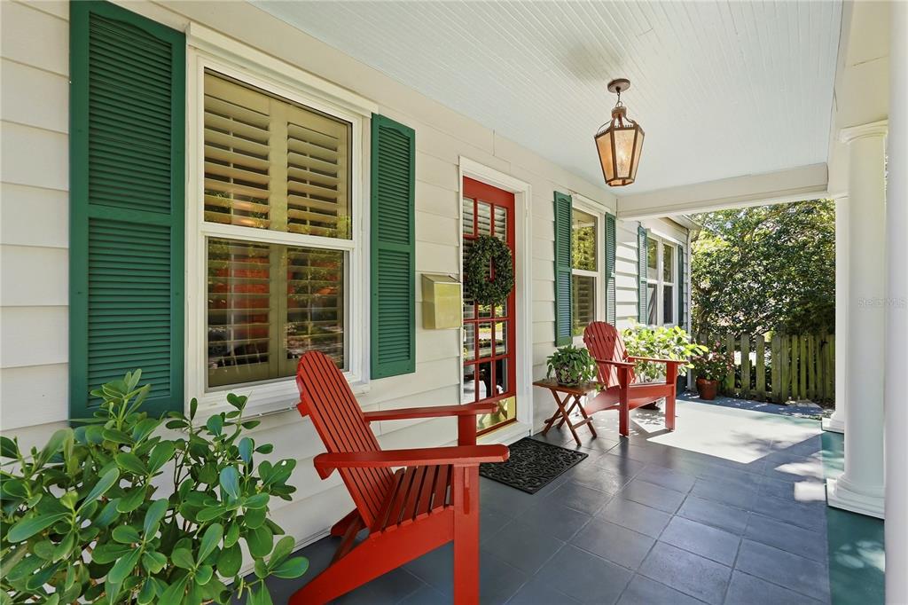 A covered front porch features two red Adirondack chairs, a red door, and green shutters — 1325 24TH AVENUE N, ST PETERSBURG, FL