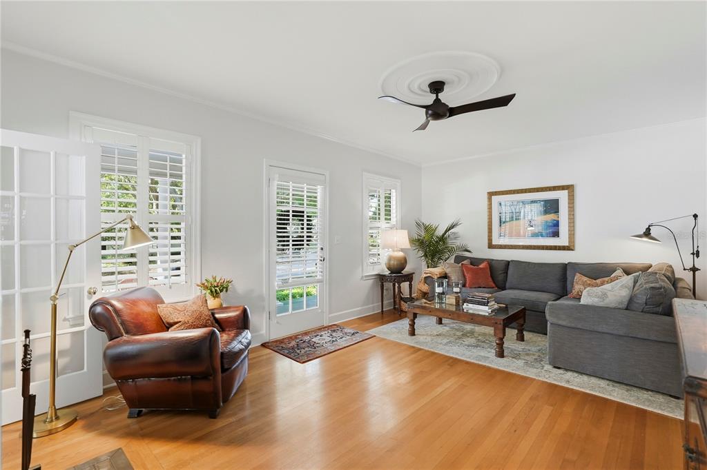 A living room features hardwood floors, a gray sectional sofa, a leather armchair, and plantation shutters — 1325 24TH AVENUE N, ST PETERSBURG, FL