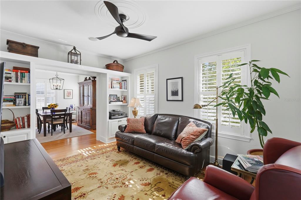 A living room features a leather sofa, a patterned rug, built-in shelves, and a ceiling fan — 1325 24TH AVENUE N, ST PETERSBURG, FL