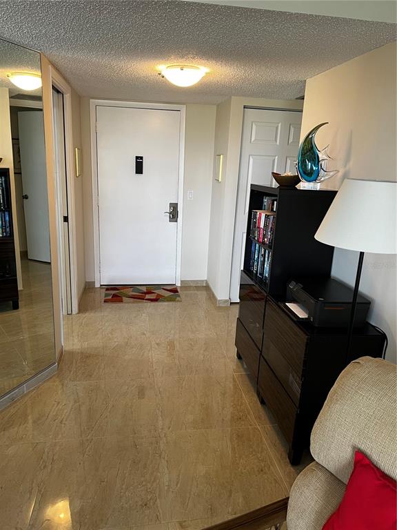 A tiled entryway features a white front door, a black bookshelf, and a floor lamp — 1102 BEN FRANKLIN DRIVE UNIT 514, SARASOTA, FL