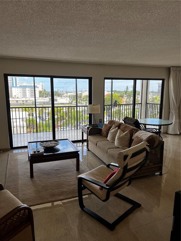 A living room features tile floors, a brown sofa, a coffee table, and large sliding doors — 1102 BEN FRANKLIN DRIVE UNIT 514, SARASOTA, FL