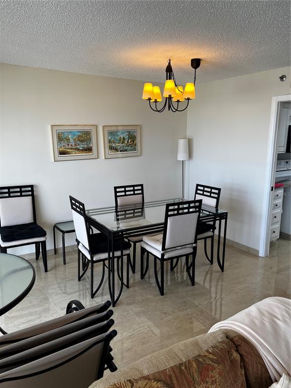 A dining area features a glass-topped table, four chairs, and a chandelier on tiled floors — 1102 BEN FRANKLIN DRIVE UNIT 514, SARASOTA, FL