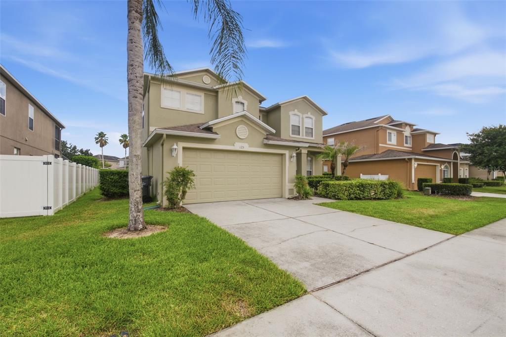 A two-story house with a beige exterior, a two-car garage, and a concrete driveway — 125 NORFOLK DRIVE, DAVENPORT, FL