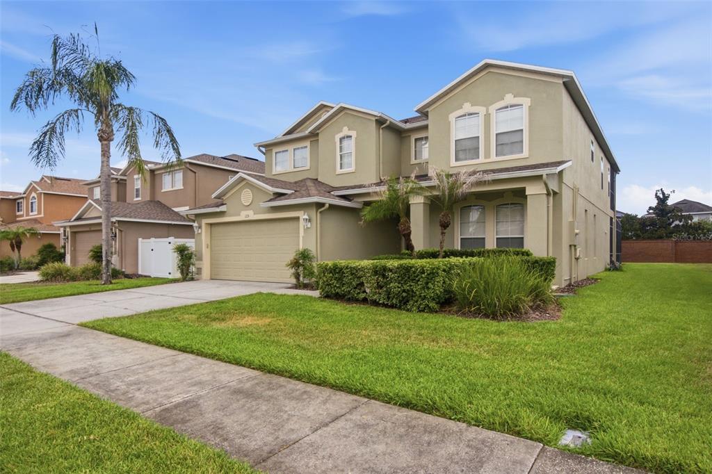 A two-story, light green suburban house with a two-car garage and a manicured front lawn — 125 NORFOLK DRIVE, DAVENPORT, FL