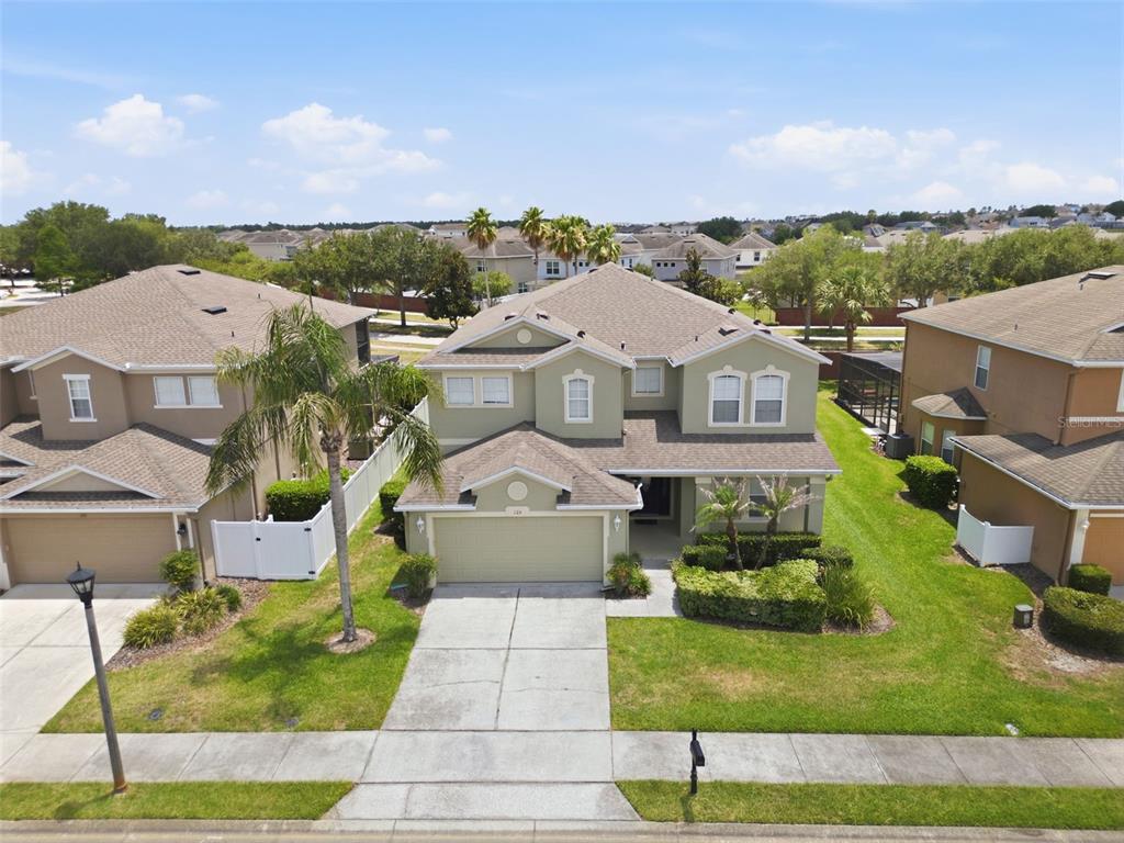 An aerial view shows a two-story suburban house with a tan exterior and attached garage — 125 NORFOLK DRIVE, DAVENPORT, FL