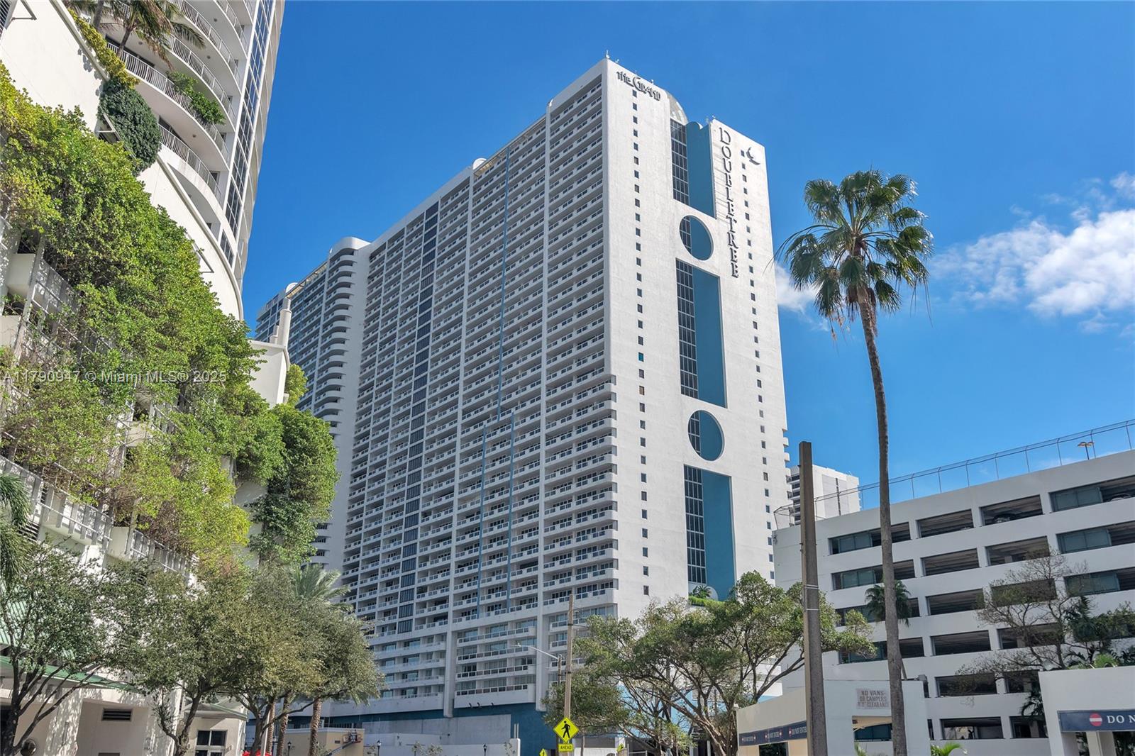 A tall white high-rise building with a DoubleTree sign stands under a clear blue sky — 1717 N Bayshore Dr # 3144, Miami FL 33132, MIAMI, FL