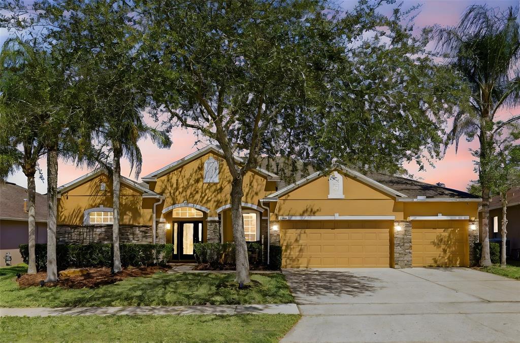A single-story house with a yellow stucco exterior, stone accents, and a three-car garage — 1356 ANNA CATHERINE DRIVE, ORLANDO, FL
