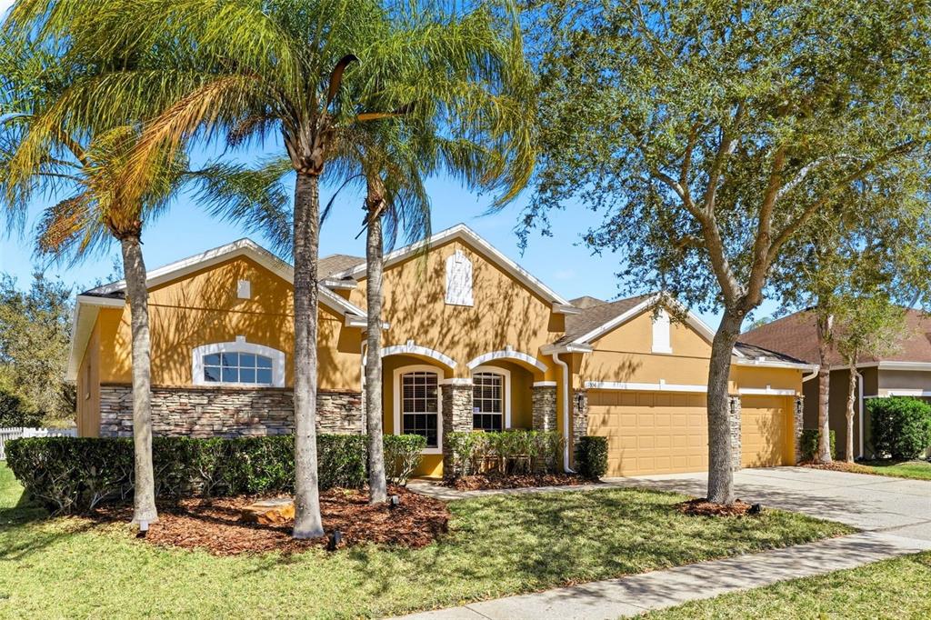 A single-story house with a tan stucco exterior, stone accents, and a two-car garage — 1356 ANNA CATHERINE DRIVE, ORLANDO, FL