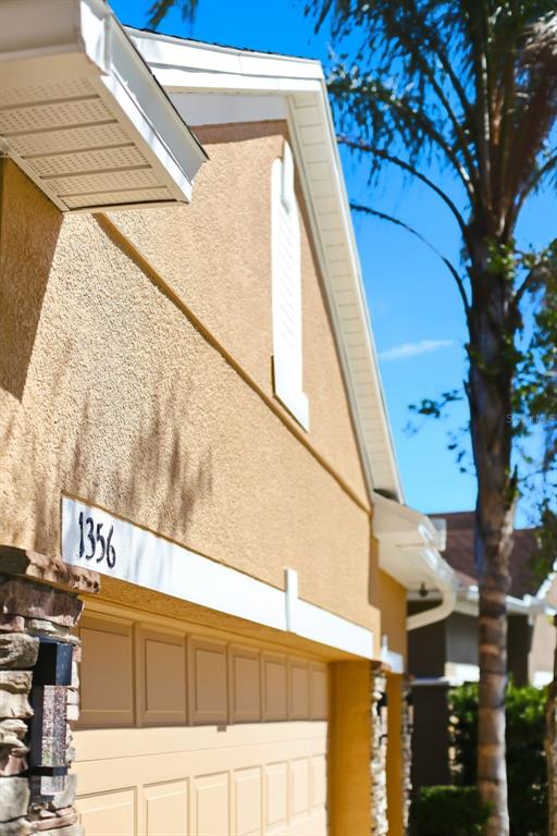A low-angle view shows the beige stucco exterior of a house with a garage door — 1356 ANNA CATHERINE DRIVE, ORLANDO, FL