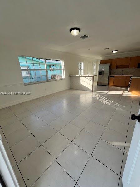 An open-concept room with white tile flooring, a kitchen with wood cabinets, and large windows — 2411 NW 65th St, Miami FL 33147, MIAMI, FL