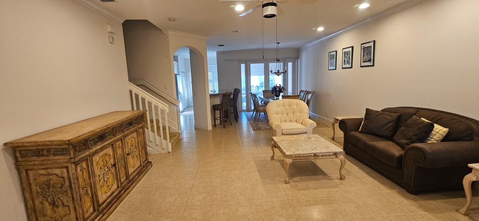 A living room with tile floors, a brown sofa, a cream armchair, and a wooden sideboard — 179 Las Brisas Circle, Hypoluxo FL 33462, HYPOLUXO, FL