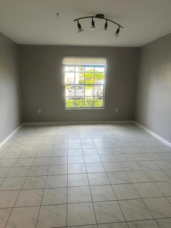 An empty room with gray walls, white tiled floors, and a four-light track fixture — 1767 FOUR MILE COVE PARKWAY UNIT 810, CAPE CORAL, FL