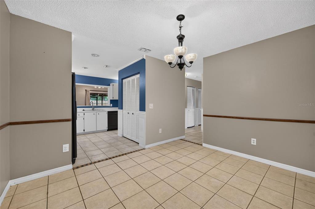 A dining area with beige walls, tile flooring, a chandelier, and an adjacent kitchen — 512 DERBY DRIVE, ALTAMONTE SPRINGS, FL