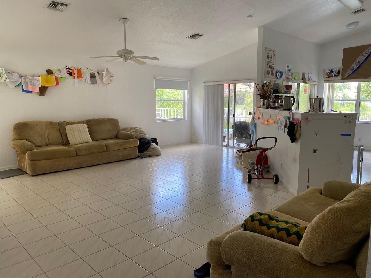A spacious living room features light tile flooring, two tan sofas, and a ceiling fan — 4080 Sea Grape Circle, Delray Beach FL 33445, DELRAY BEACH, FL
