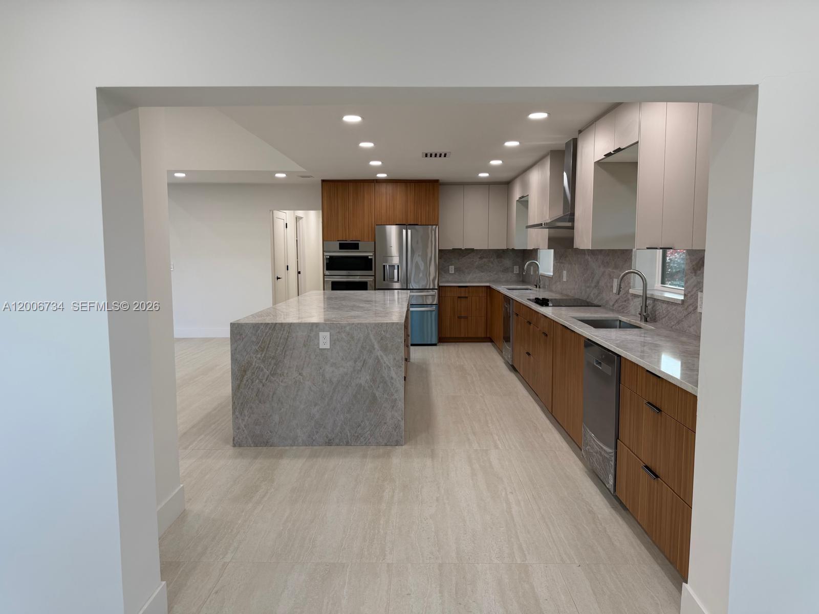 A modern kitchen features wood-toned cabinetry, a large stone island, and stainless steel appliances — 7917 Chula Vista Cres, Boca Raton FL 33433, BOCA RATON, FL
