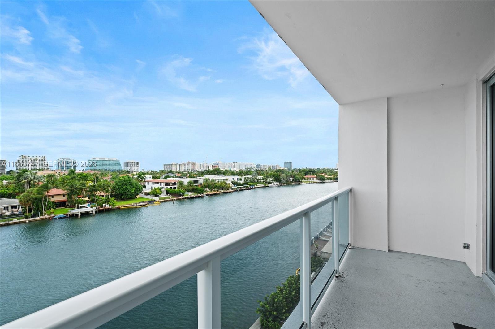 A balcony with a glass railing overlooks a canal and a residential neighborhood — 9381 E Bay Harbor Dr # 603S, Bay Harbor Islands FL 33154, BAY HARBOR ISLANDS, FL