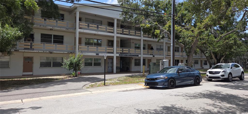 A three-story apartment building with balconies and two cars parked in front — 911 WASHINGTON AVENUE UNIT 304, LARGO, FL