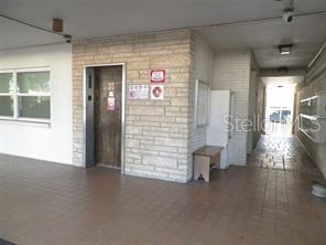 A covered entryway features a stone wall, an elevator, and a hallway with mailboxes — 911 WASHINGTON AVENUE UNIT 304, LARGO, FL