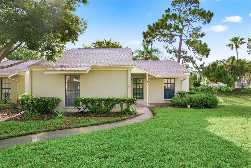 A single-story stucco house with a shingled roof, a front walkway, and a grassy lawn — 18 WINDRUSH BAY DRIVE, TARPON SPRINGS, FL